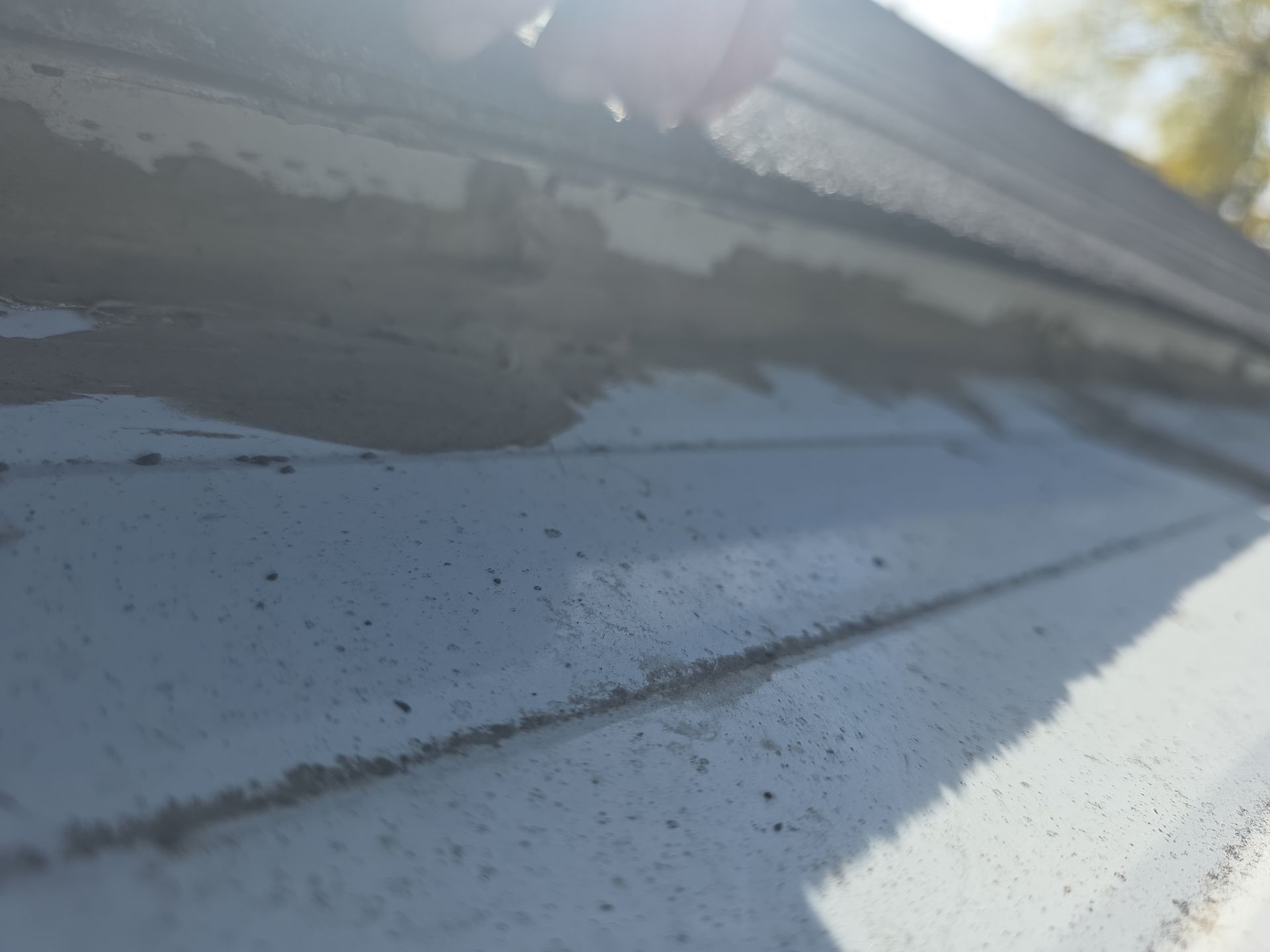 Close-up of roof flashing and shingle detail showing wear that needs repair